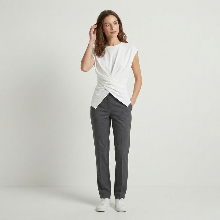 Woman in cream ruched knit top with drop shoulders and cross-tie back detail, soft ribbed texture