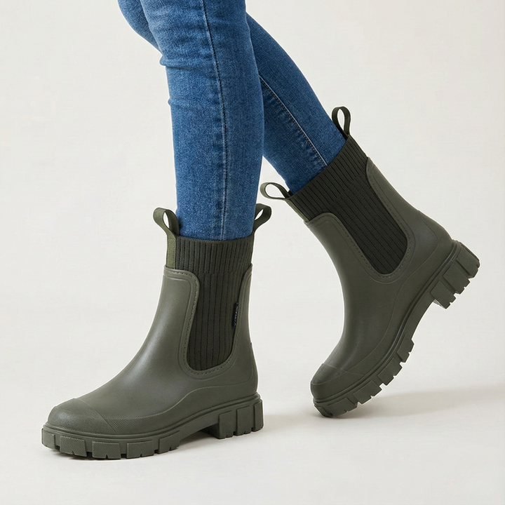 Black minimalist rain boots with matte waterproof finish and textured sole, styled on urban pavement