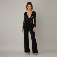 Woman in white crochet lace jumpsuit with deep V-neckline, flared legs, and cinched waist belt