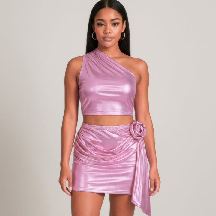 Woman in silver metallic one-shoulder crop top and mini skirt set with rose detail, shimmering stretch fabric