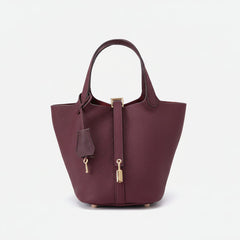 Burgundy structured basket handbag with metallic twist-lock clasp and faux-leather finish, held against neutral background