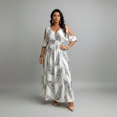 Woman in flowy maxi dress with cold-shoulder neckline, split hem, and botanical print in woven polyester