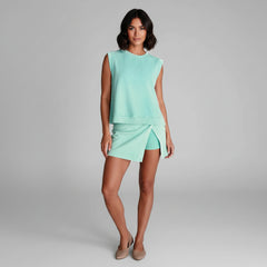 Woman wearing white ribbed tank top and black split hem skort set, athletic silhouette with skort overlay detail