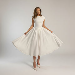 Woman in flowing A-line maxi dress with cinched waist, soft draping, full-length silhouette in natural light