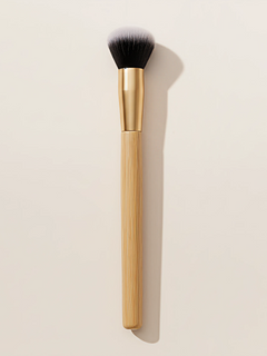 Professional bamboo makeup brush with dense synthetic bristles and natural bamboo handle on white surface
