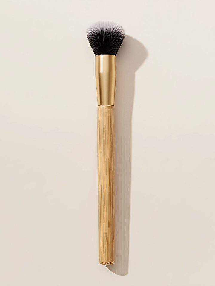 Professional bamboo makeup brush with dense synthetic bristles and natural bamboo handle on white surface