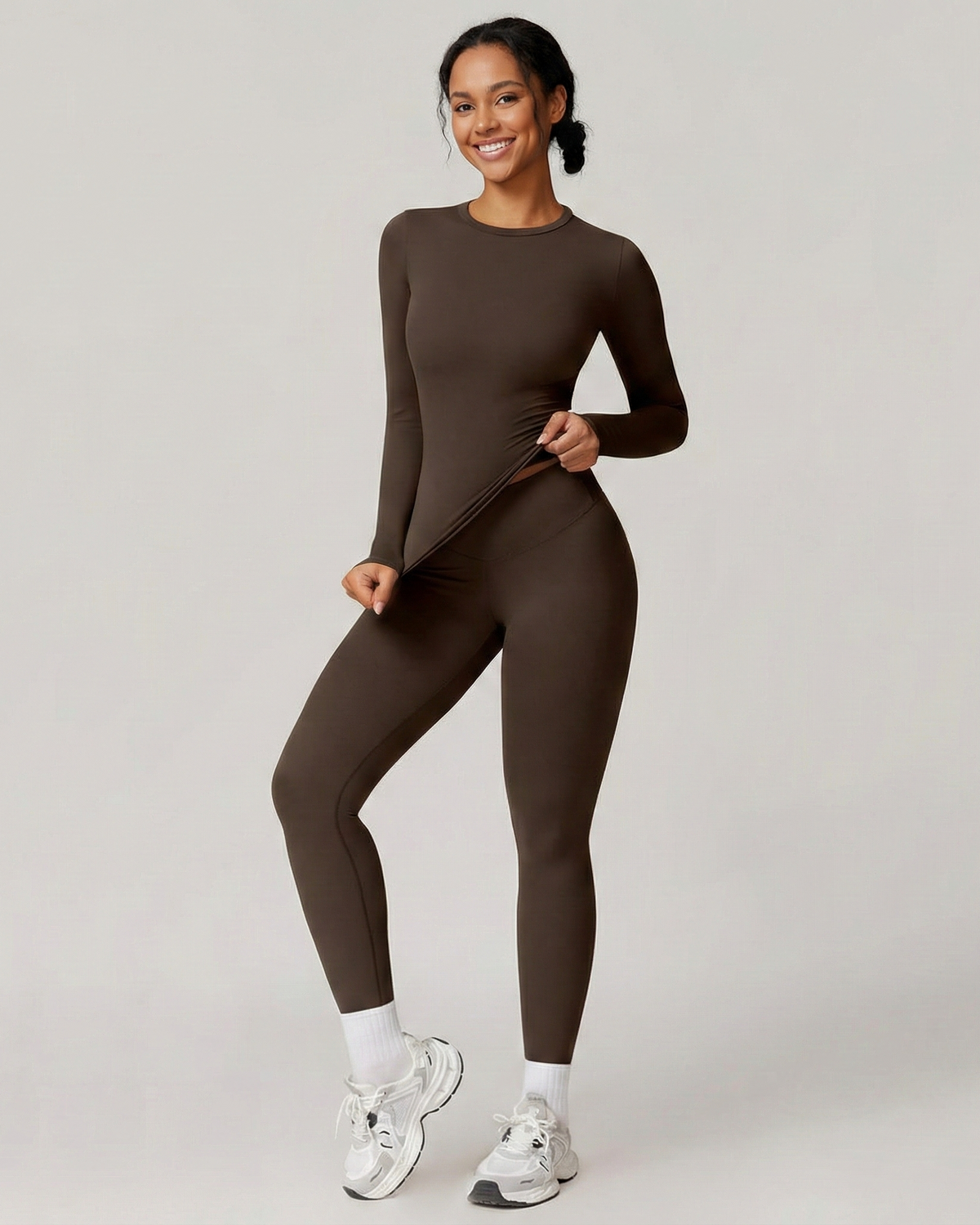 Woman in black ribbed two-piece set with high-waist leggings and fitted top, neutral studio backdrop