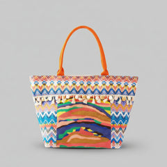 Orange and multicolor boho print tote bag with playful pom pom fringe detailing and zipper closure