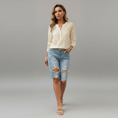 Woman wearing beige V-neck button blouse with front pockets, soft polyester-elastane blend, relaxed fit