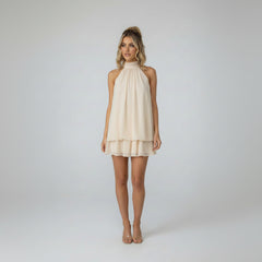 Woman in sleeveless polka-dot mini dress with tie-back detail, slim-fit silhouette, textured fabric