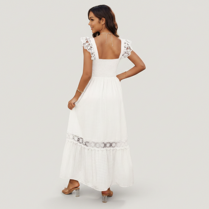 Woman wearing a white dress with lace details on a plain background