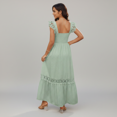 Woman wearing a light green dress with lace details on a gray background