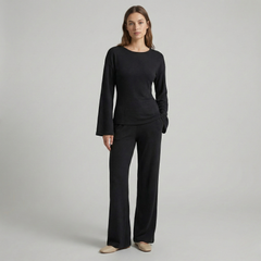Woman in cream ribbed knit flare sleeve top and matching bottoms, fitted silhouette, neutral backdrop